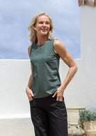 Woman wearing a relaxed fit 100% cotton green sleeveless top and black pants standing outdoors