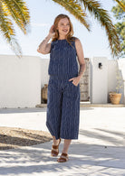 Woman wearing a navy based white striped print wide leg, 3/4 length cotton pants with side zipper 
