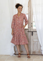 Woman poses in cotton tiered over the knee dress with 3/4 sleeves, buttoned bodice and V-neckline