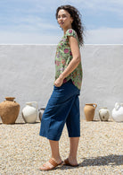 Woman wearing a moss green based multi-coloured folk art style florals 100% cotton top 