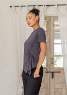 Woman wearing Dark grey women’s twist-front T-shirt, stretch rayon short-sleeve top with subtle draped knot in a home setting