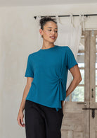Woman wearing Twist-front teal rayon T-shirt for women, short-sleeve crew-neck top with soft draped knot detail