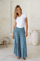 Woman posing in 100% rayon super wide legged pull on pants in blue based floral print.