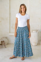 Woman wearing a basic white t-shirt and super wide leg blue floral pants in a bright room.