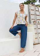 Woman wearing a neutral based floral print cotton top with blue pants.
