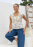 Woman wearing a neutral based floral print 100% cotton top with coconut buttons.