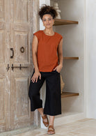 Woman wearing 100% cotton top in orange brushetta colour paired with plain black pants.