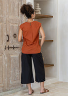 Woman wearing 100% cotton top in orange brushetta colour with subtle keyhole and button closure at the back