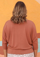 Back view of woman wearing a 3/4 sleeve rayon batwing round neckline dusty pink top.