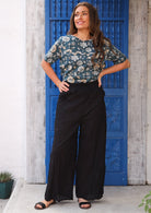 Model poses in high waisted women's black cotton pants with hands on hips