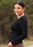 Side view of woman wearing black long sleeve stretch v-neck soft rayon top.