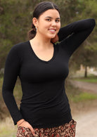 Woman with dark hair wearing black long sleeve stretch v-neck soft rayon top.
