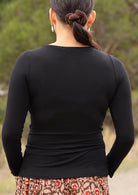 Back view of woman wearing black long sleeve stretch v-neck soft rayon top.