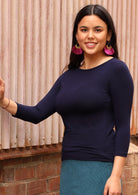 Woman wearing a rayon boat neck navy blue 3/4 sleeve top with green skirt.