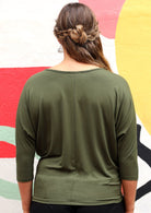 Back view of woman wearing a 3/4 sleeve rayon batwing round neckline olive green top.