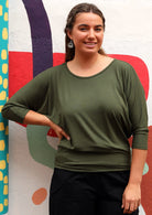 Woman wearing a 3/4 sleeve rayon batwing round neckline olive green top.