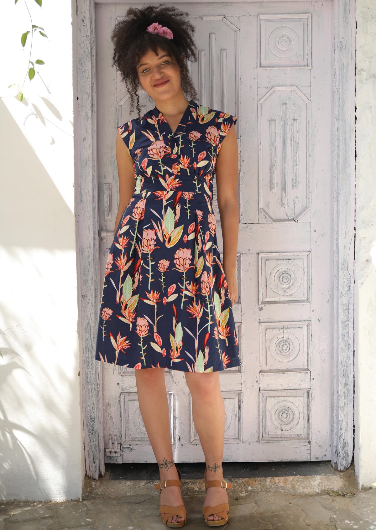 Woman wearing V-neck Cotton Short Sleeve Dress tailored Native Floral Navy background, pink and green flowers 
