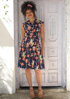 Woman wearing V-neck Cotton Short Sleeve Dress tailored Native Floral Navy background, pink and green flowers 