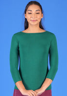 Woman with dark hair wearing a rayon boat neck green 3/4 sleeve top.