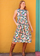 Woman wearing pastel patches designed , sleeveless dress with right hand in pocket 