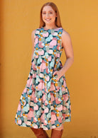 Model in 3 tiered high neck cotton dress with hands in pockets 