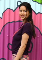 Side view of woman wearing a wide neck mod purple stretch rayon boat neck top