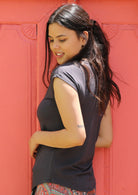Back view of woman with dark hair wearing a dark grey v-neck short cap sleeve rayon top