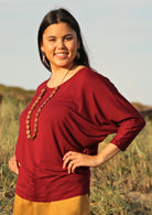 Woman wearing a 3/4 sleeve rayon batwing round neckline maroon top.