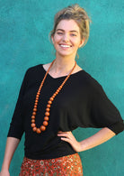 Woman with blonde hair wearing a 3/4 sleeve rayon batwing v-neck black top.