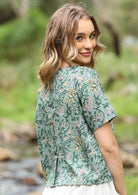 Woman in cotton short sleeve floral print top with decorative buttons down the centre of the back