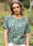 Woman stands in 100% cotton floral print top with high round neckline and T-shirt sleeves
