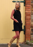 Woman wears retro style cotton corduroy tunic in black with long sleeve top and leggings in dusty pink underneath