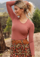 Woman wearing a round neck dusty pink long sleeve rayon top with a floral high waisted skirt.