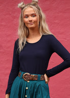Woman with blonde hair wearing a round neck navy blue long sleeve rayon top.