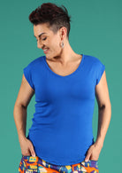 Woman with short dark hair wearing a blue v-neck short cap sleeve rayon top